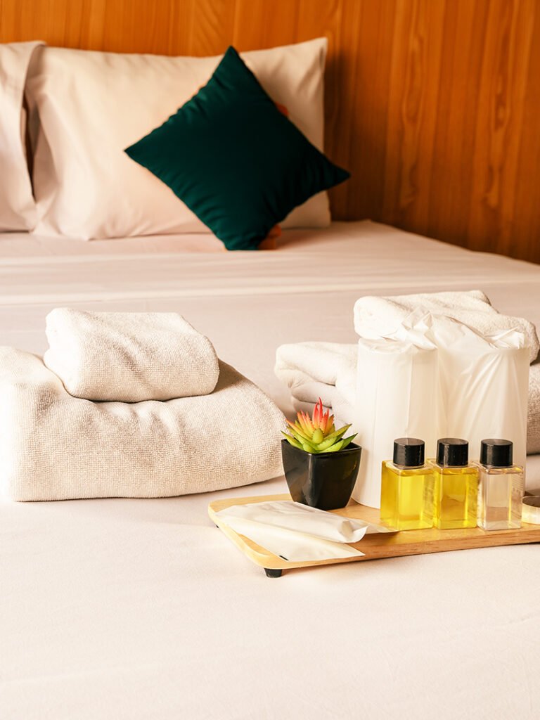 Hotel hospitality setting with bed, pillows and folded white towels.